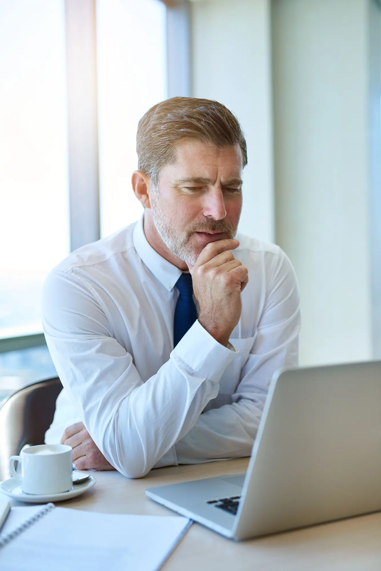 Handsome mature businessman reviewing financial audit reports on laptop for not-for-profit and charity organisations in NZ
