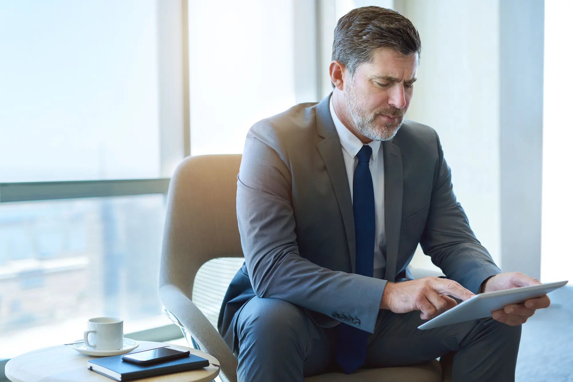 Auckland accountant reviewing financial reports with laptop and calculator in a modern office.